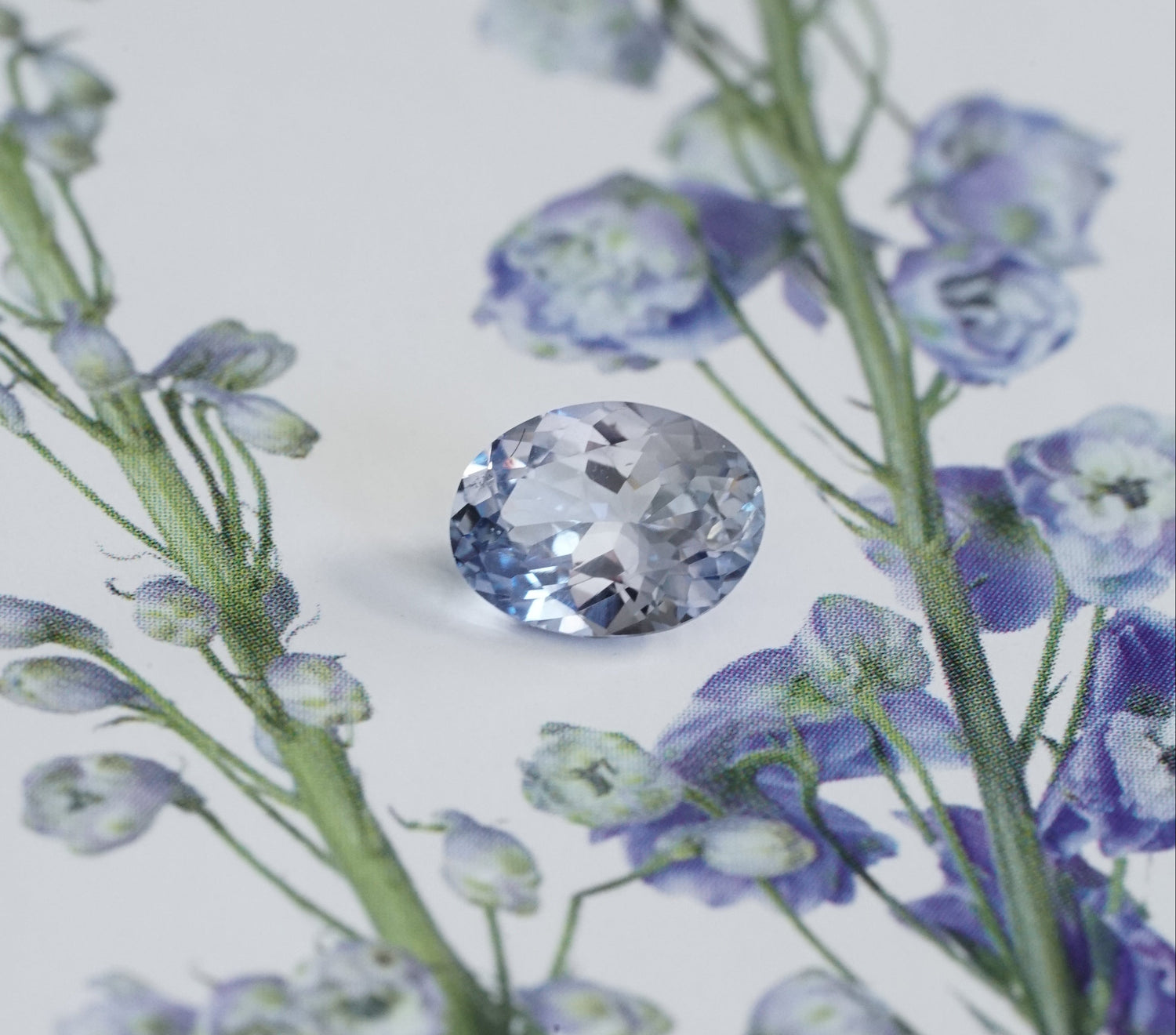 light blue sapphire between blue flowers on a light background