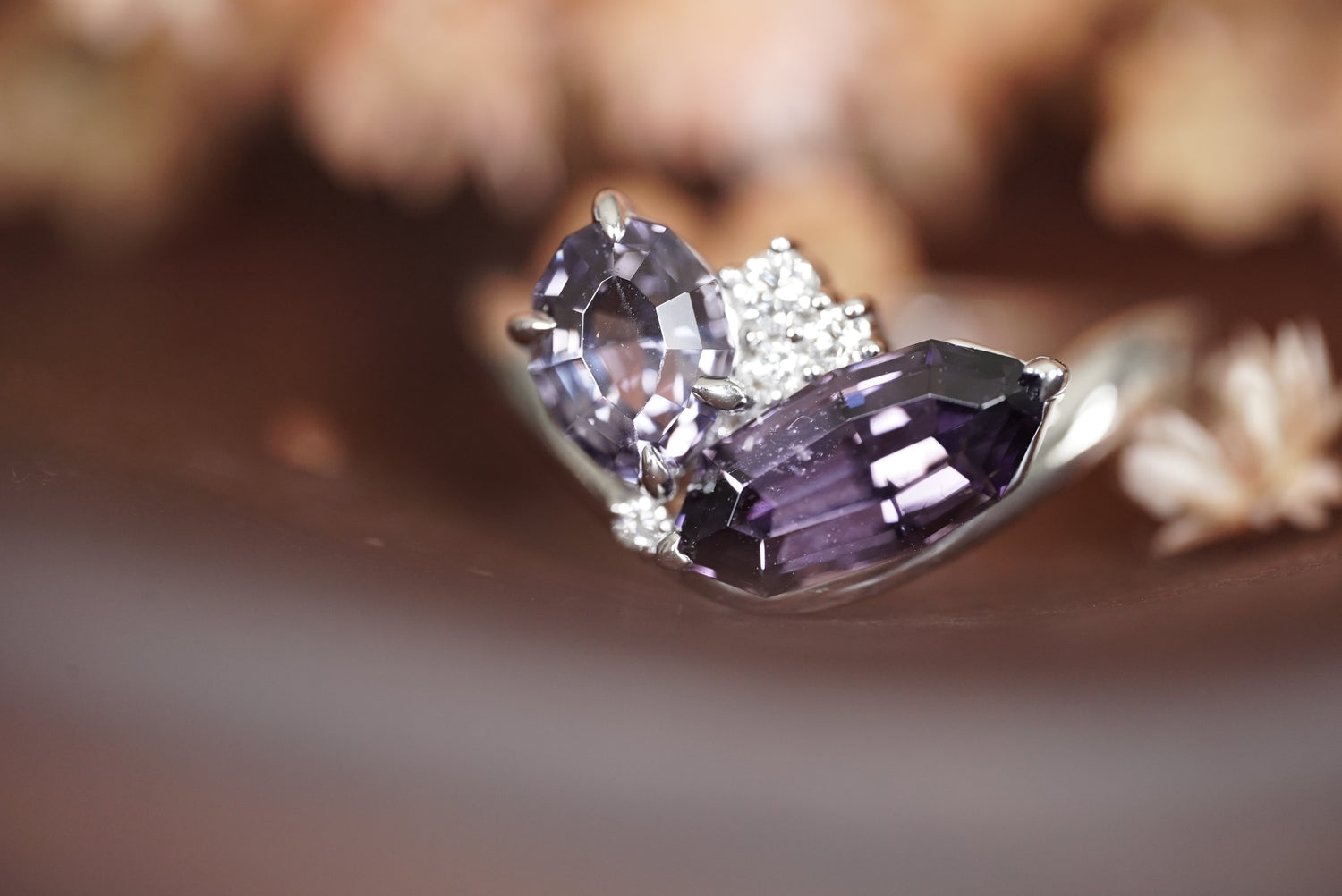 Close-up of a white gold purple gemstone ring on a blurred background