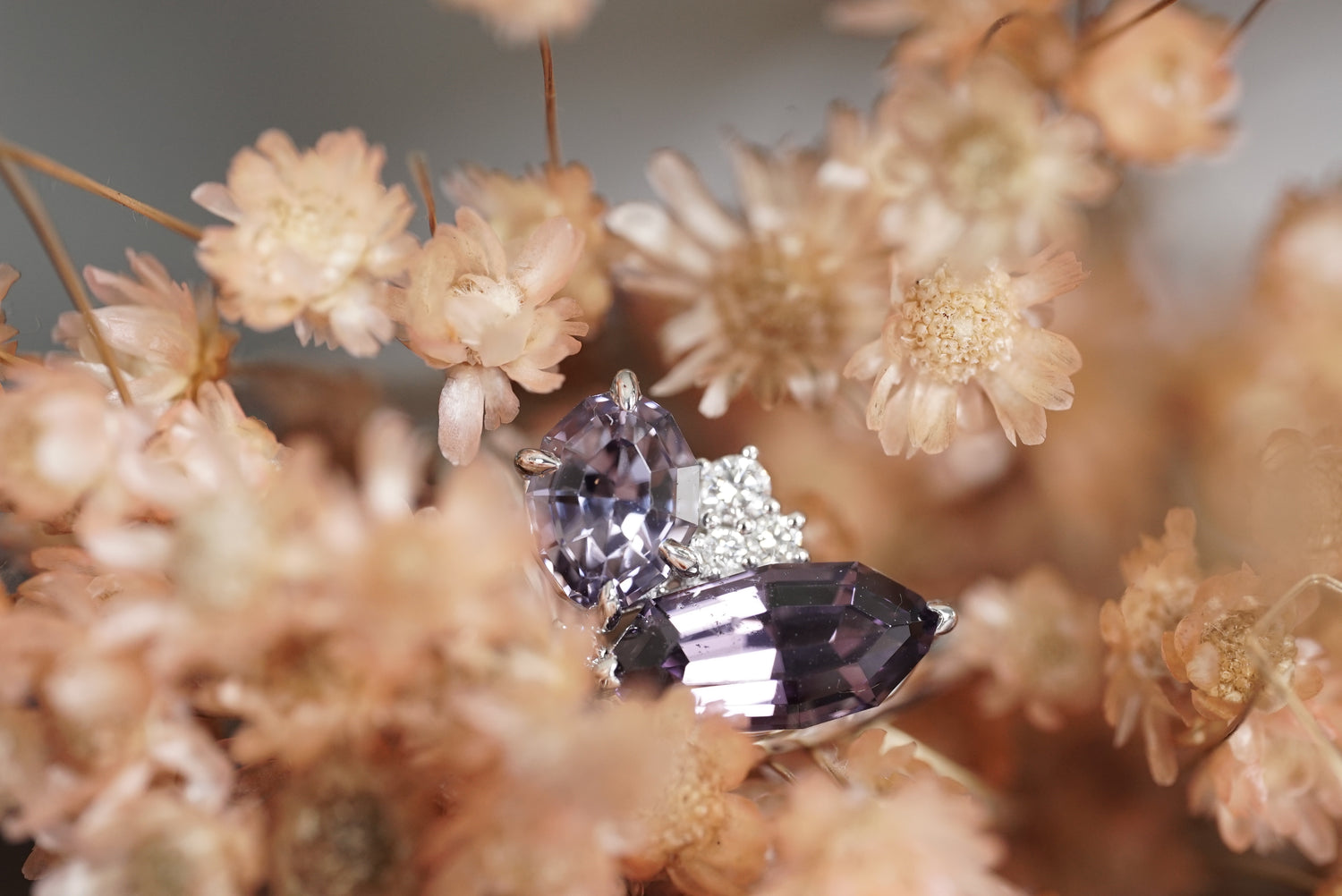 Diamond ring with a purple gemstone surrounded by dried flowers