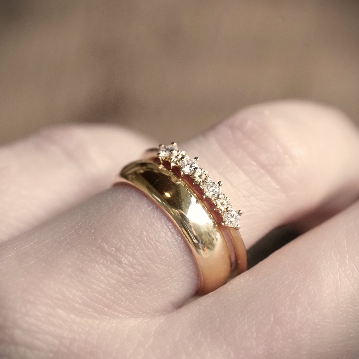 Gold ring with diamonds on a finger against a blurred background