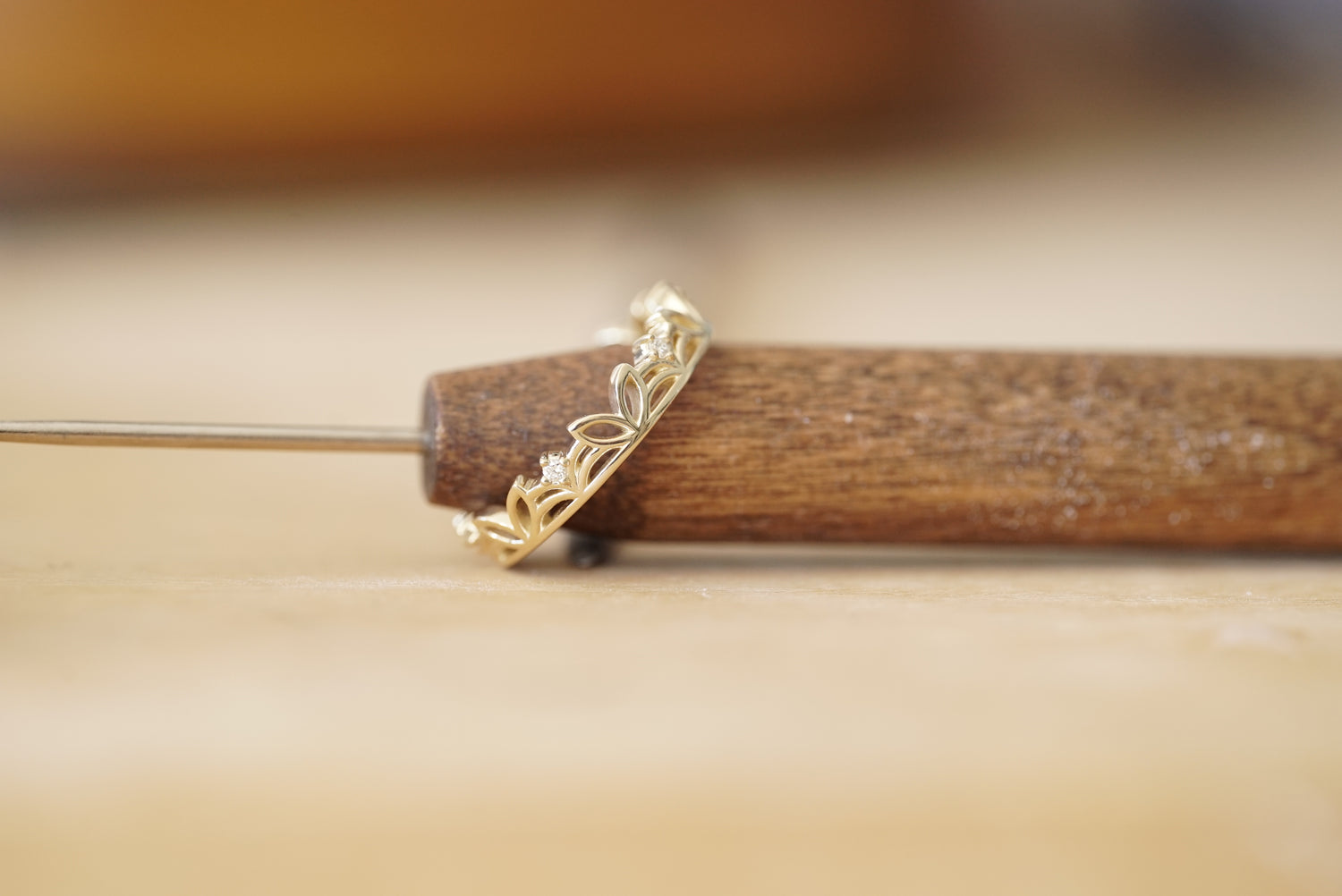 Gold ring with diamonds on a wooden stick against a blurred background