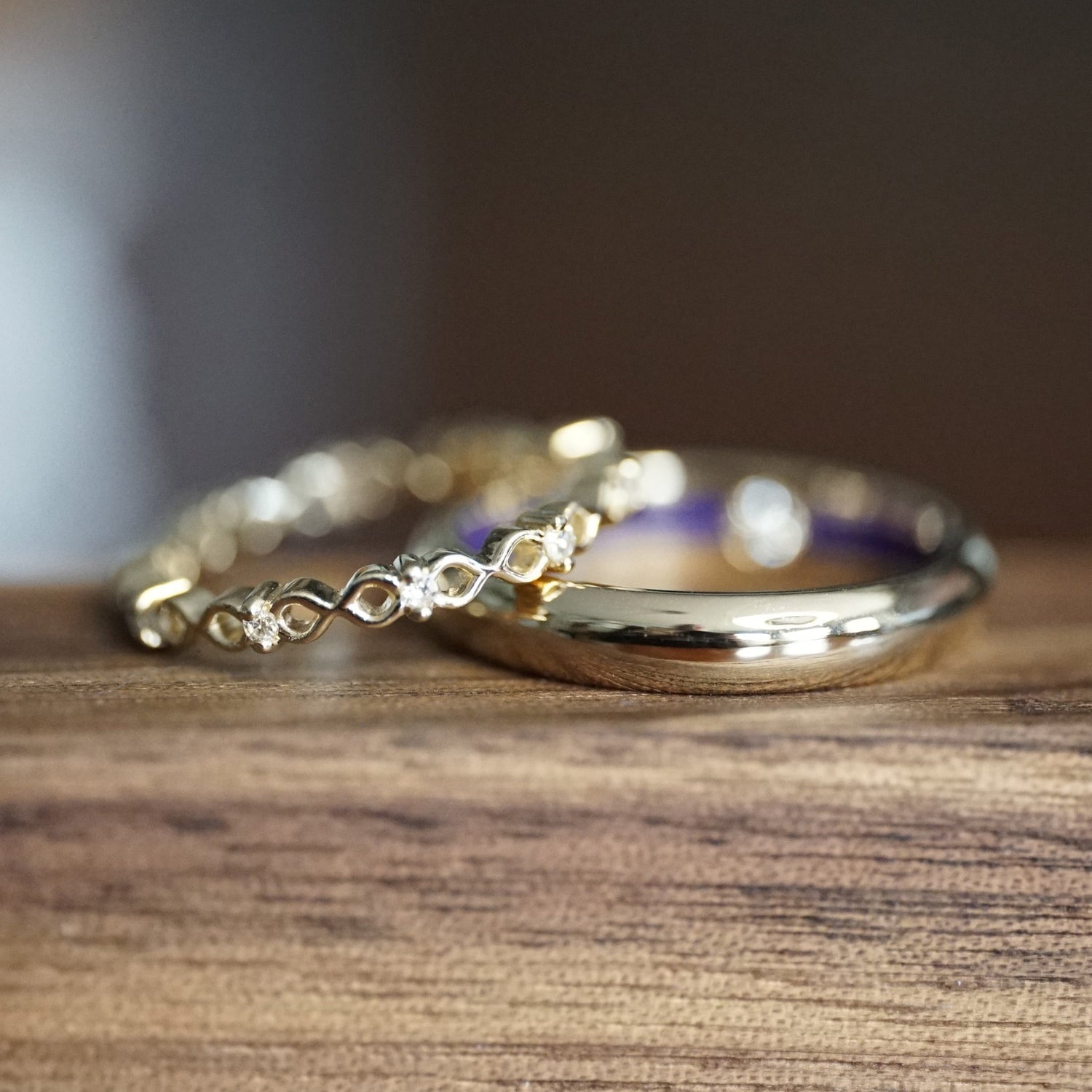 a custom yellow gold wedding set featuring diamonds and blue resin on a wooden display
