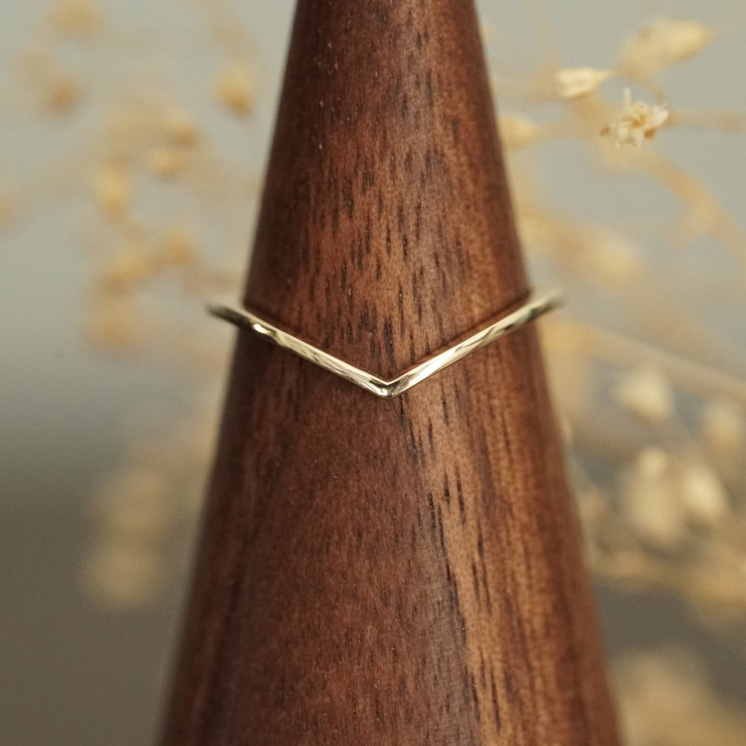 a 14k yellow gold shadow style band rests on a wood display
