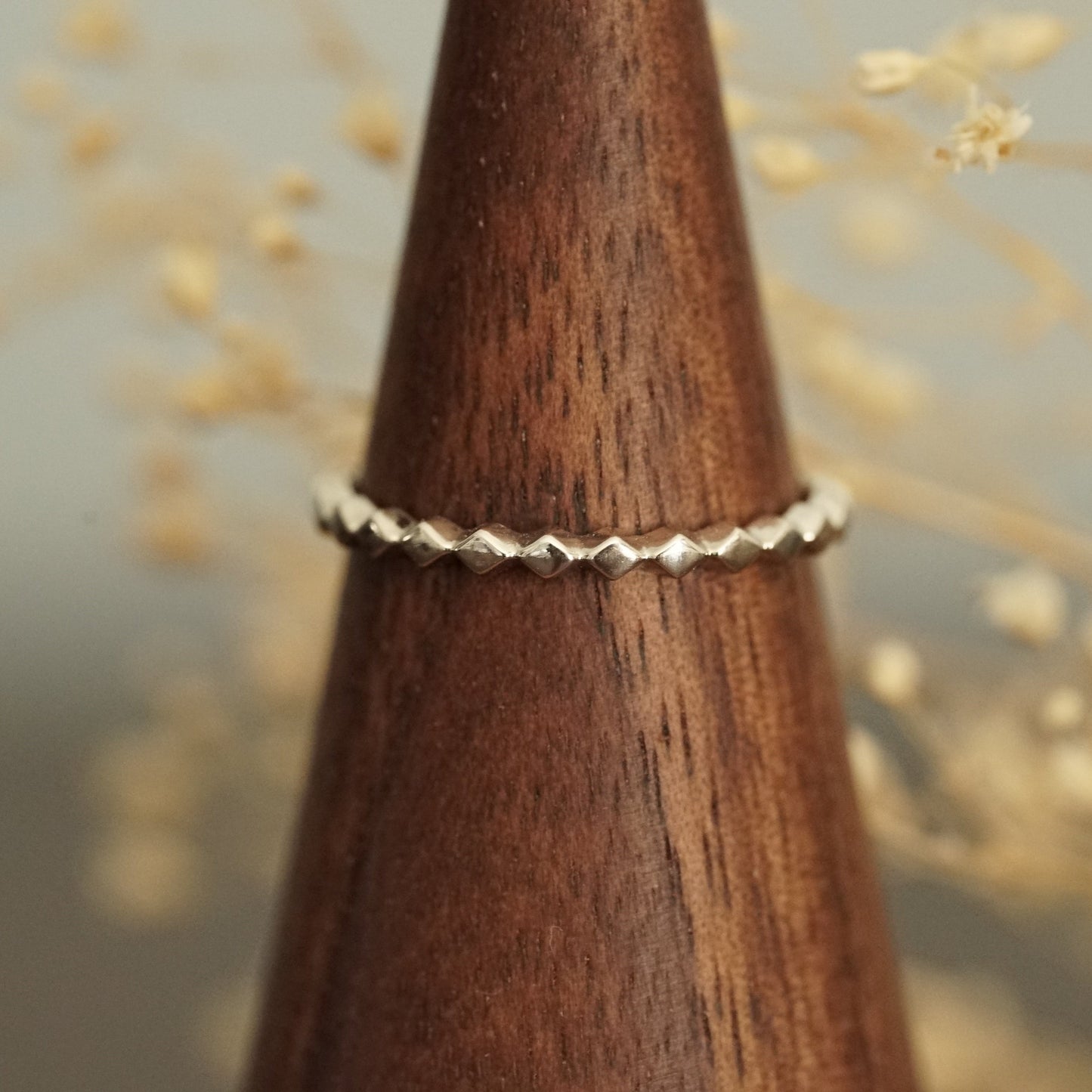 a white gold ring rests on a wood finger display