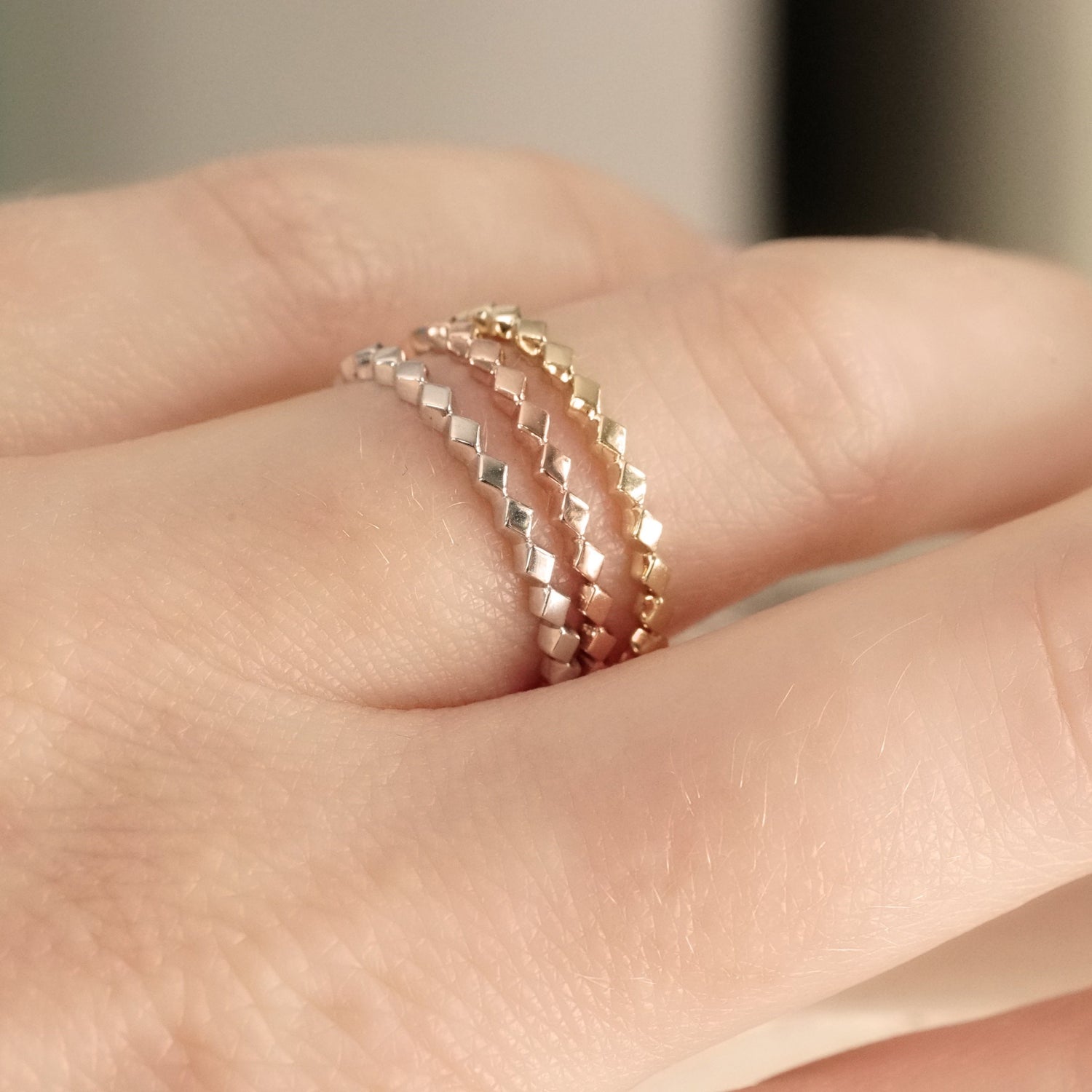 stacking bands shown in white yellow and rose gold on a light skinned left hand
