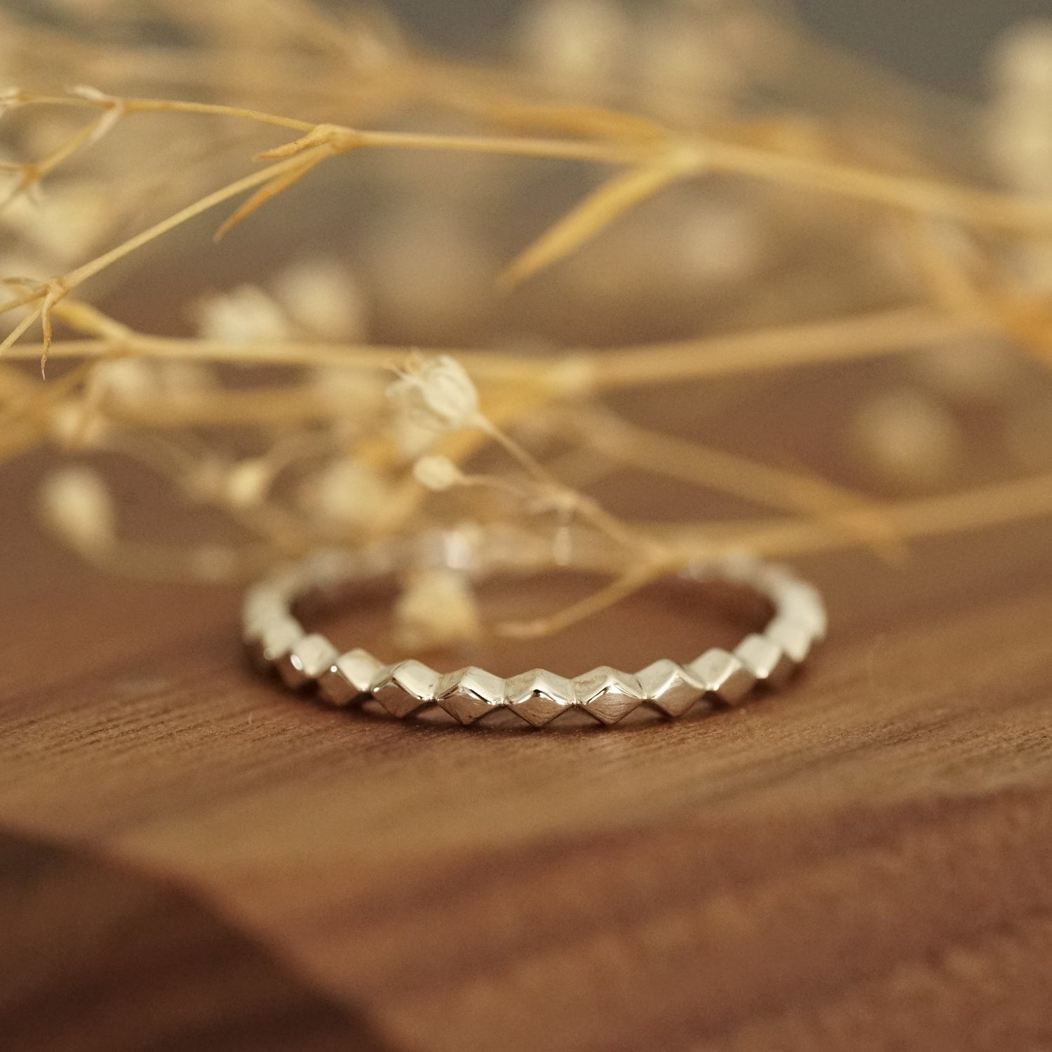 a white gold ring rests on a wood base with white flowers