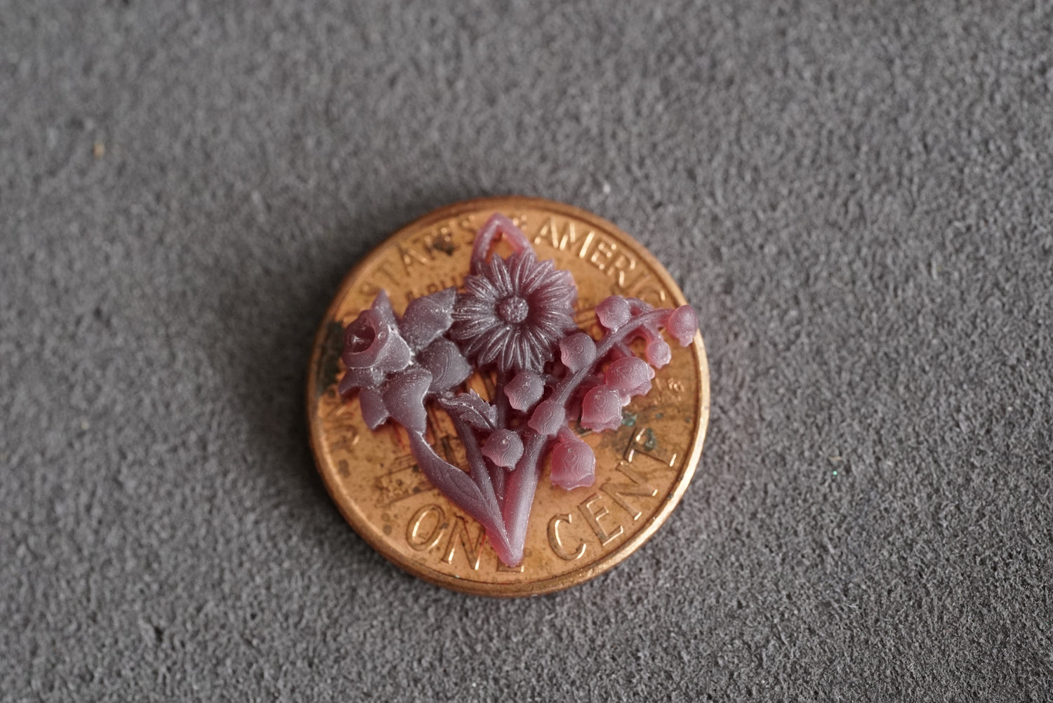 a 3d printed wax model of a custom mothers pendant shown on a penny for scale