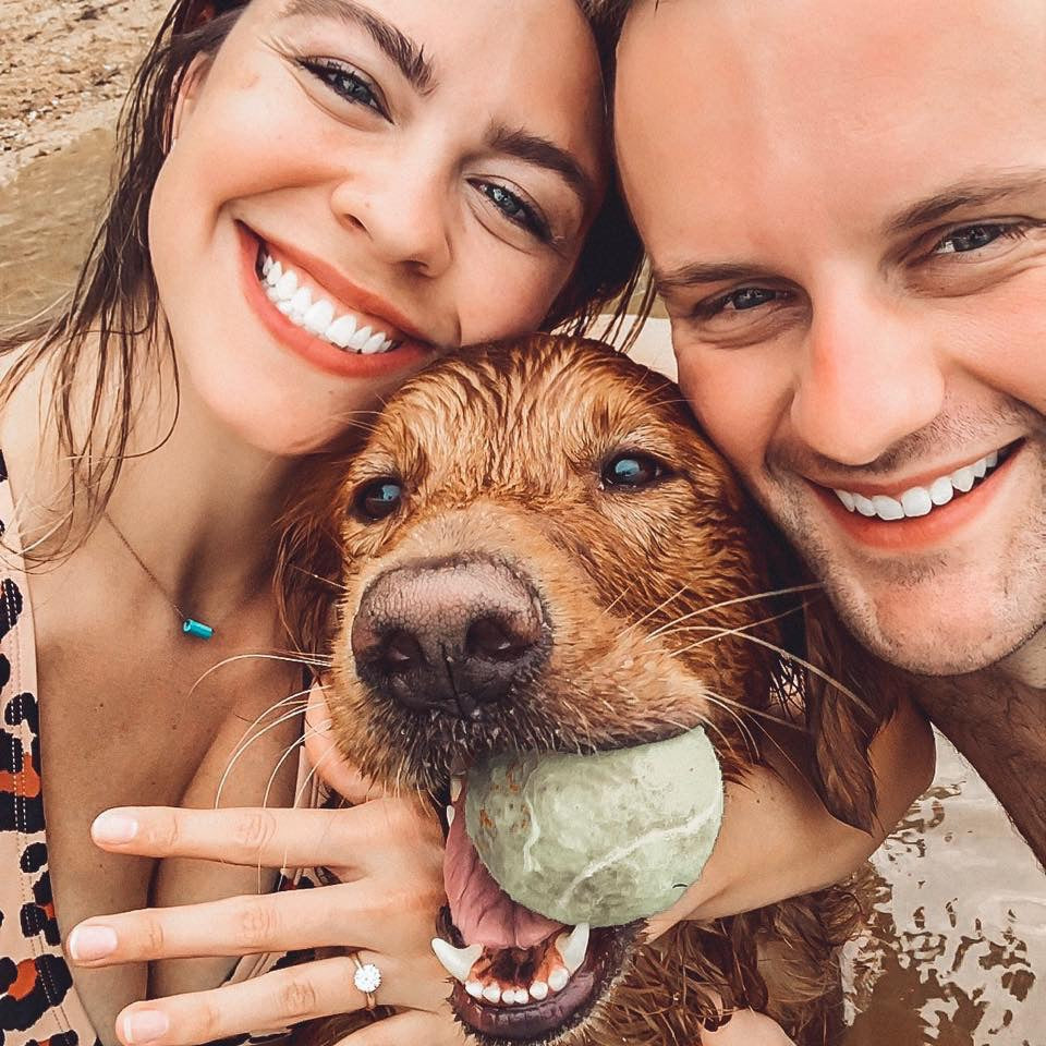 A happy newly engaged couple with a very happy dog