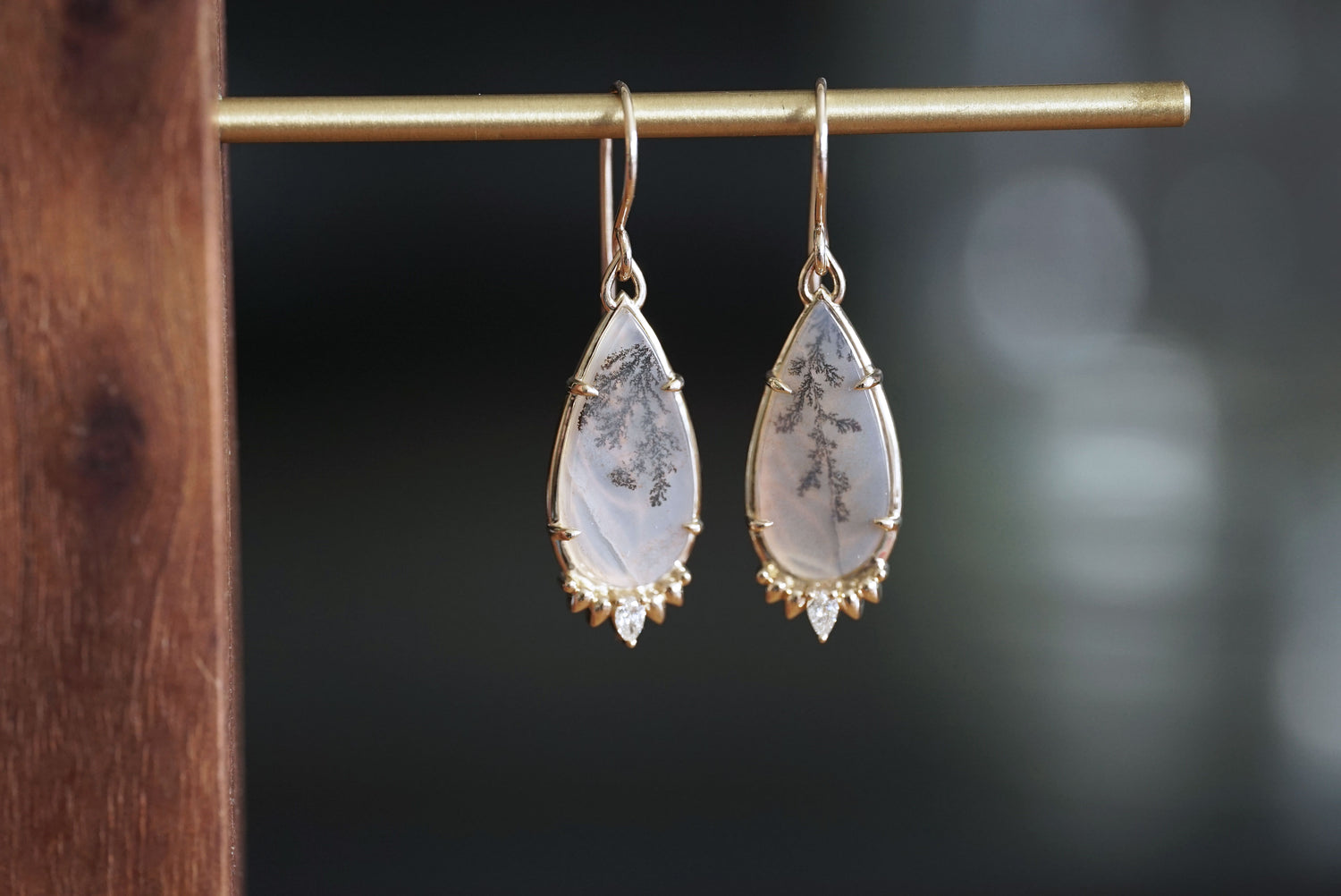 Teardrop-shaped earrings with gold accents on a dark background