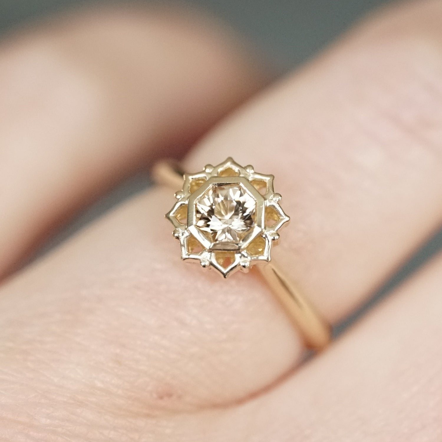 Yellow Gold gold ring with octagon tourmaline on a finger against a neutral background