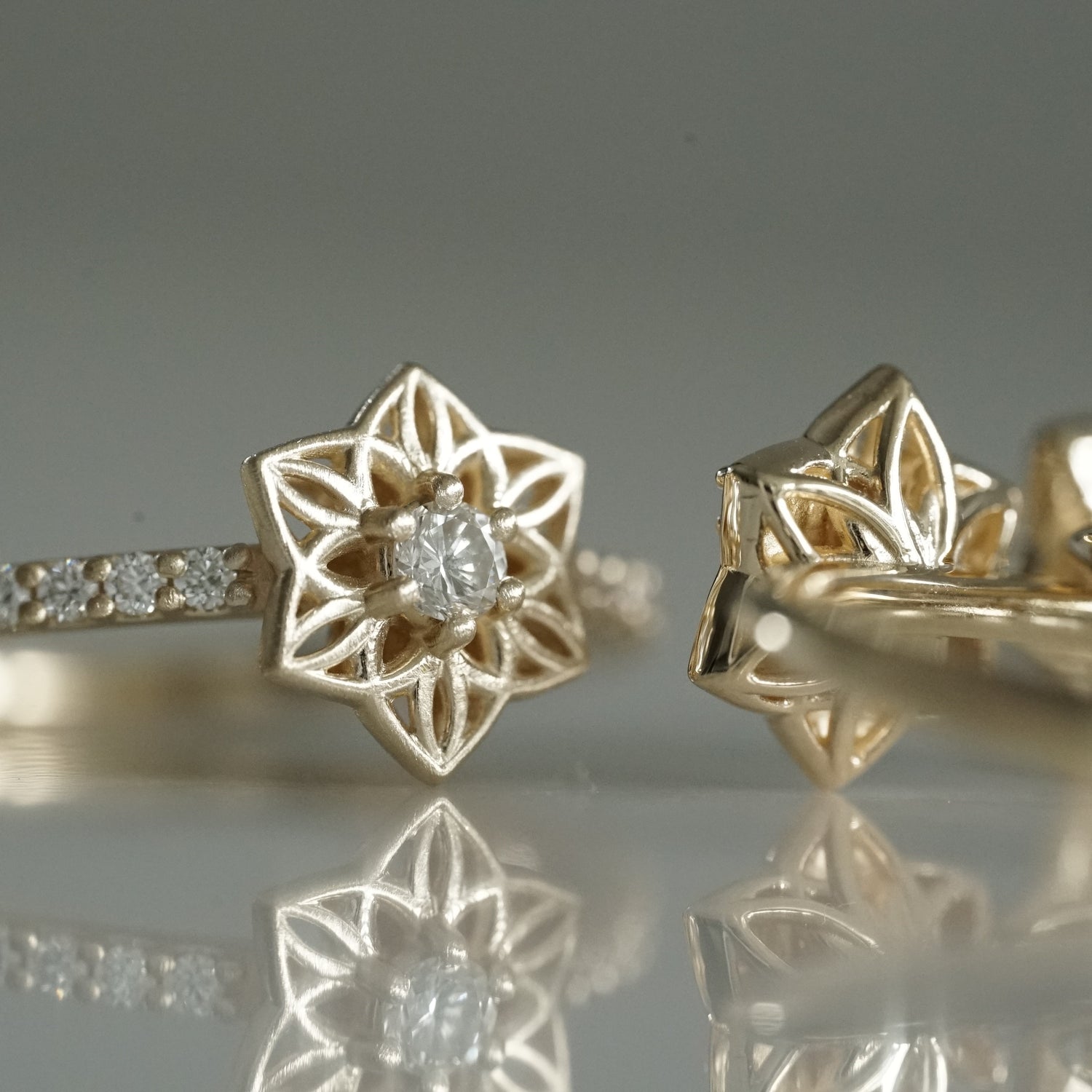 a macro photo of a matte finish daffodil inspired ring with a single prong set diamond in the center and shared prong diamonds on the shank and a detail view of the backside of another ring