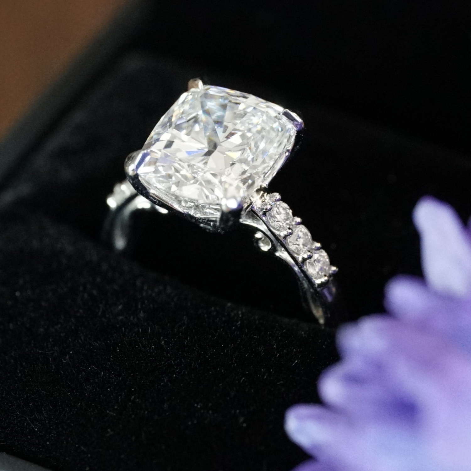 a platinum and diamond engagement ring in a black ring box with purple flowers