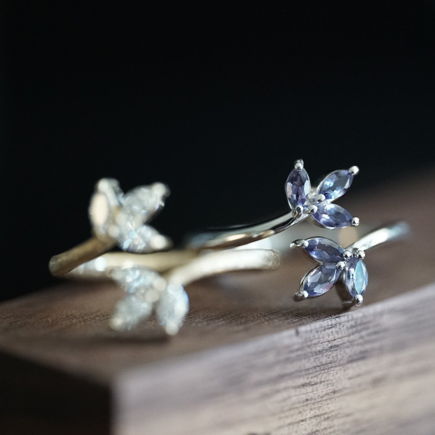 a macro photo of a white gold and iolite leaf inspired stacking ring on a wood grain display