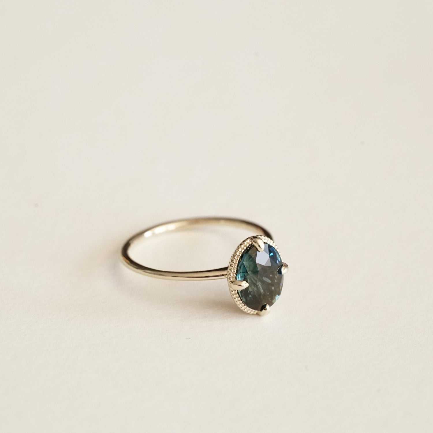 a yellow gold ring with an ornate open wirework basket on a matte white background