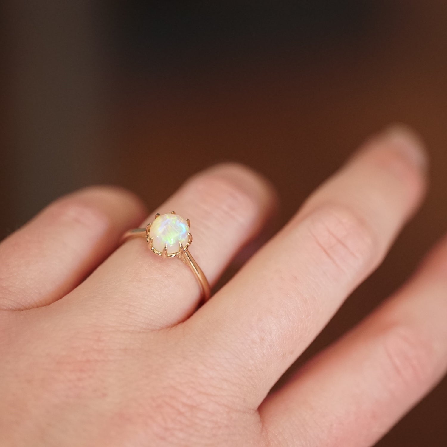 a yellow gold and opal ring on a light skinned left hand