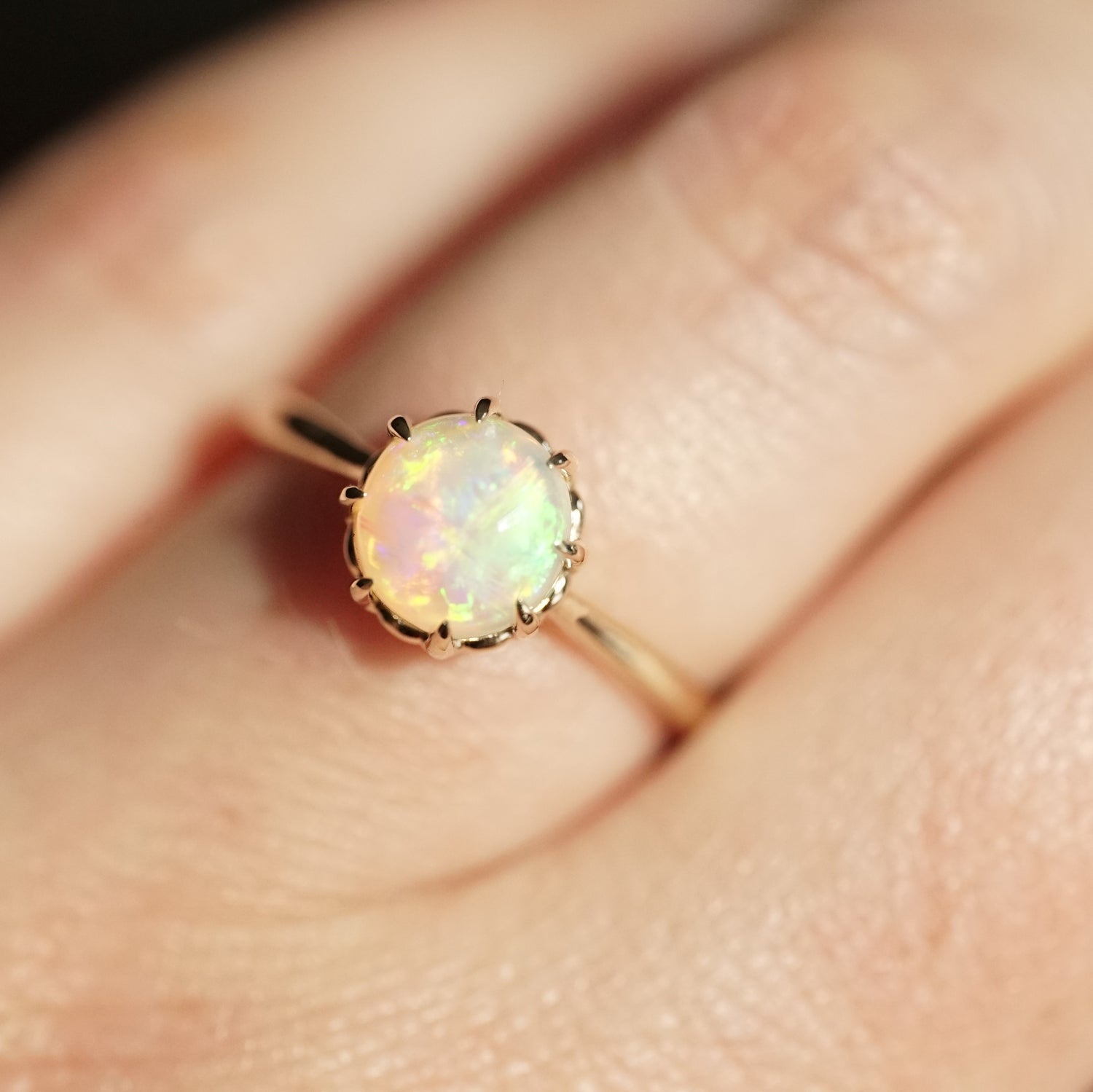 a yellow gold and opal ring on a light skinned left hand