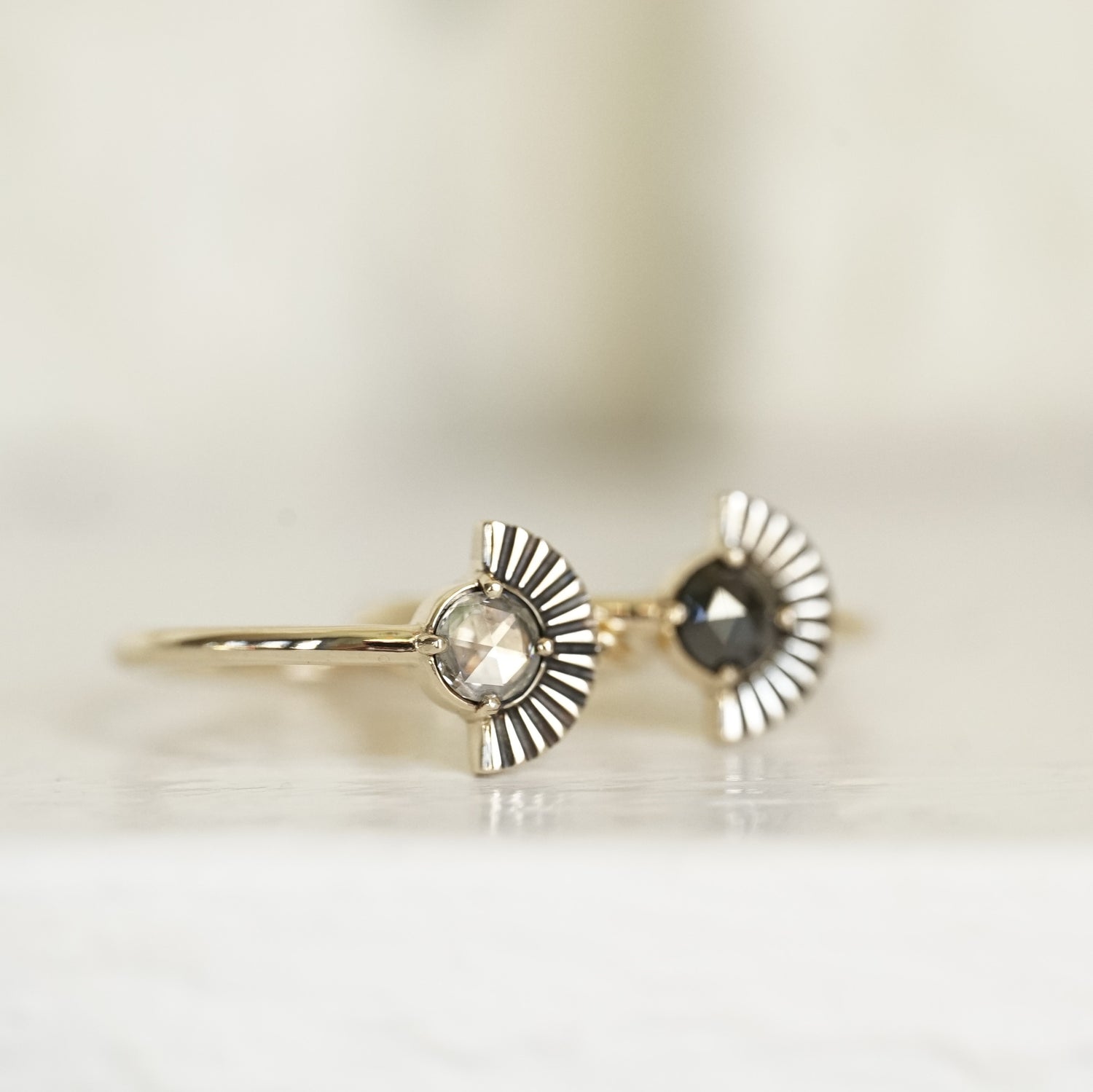 a macro photo of a rose cut white diamond ring with deco fan element to one side on a glossy white background