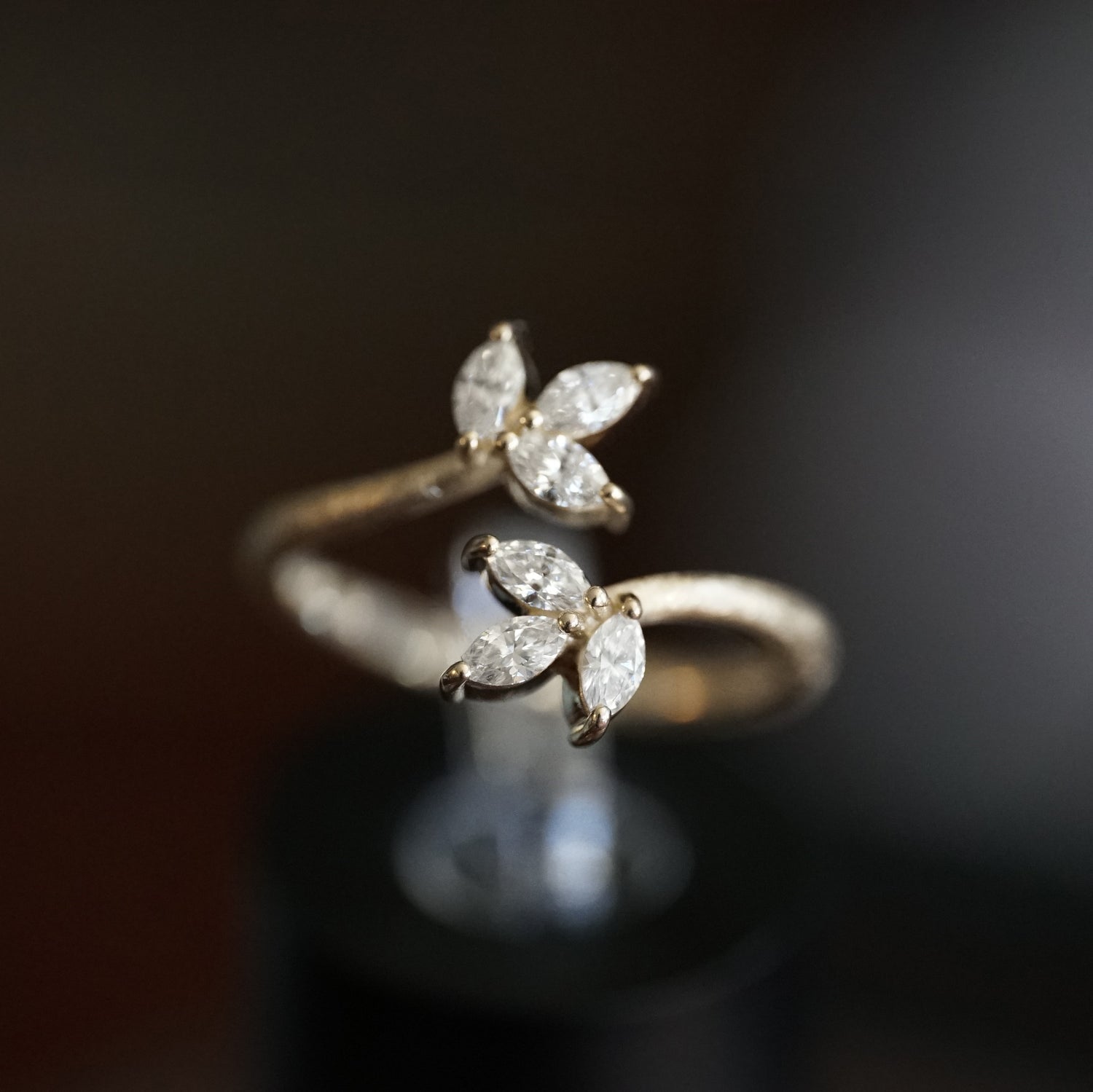 a macro photo of a yellow gold ring with 6 marquise cut diamonds in a leaf design