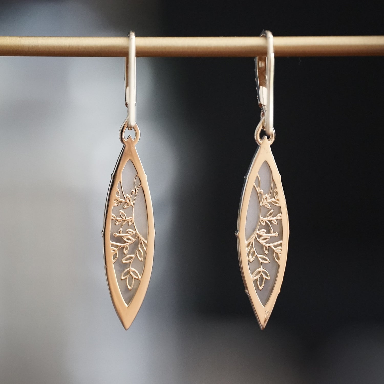 a pair of yellow gold drop earrings featuring dendritic agates rotated to show a detailed floral design on the back