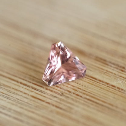 a 0.85 ct pink tourmaline trillion rests on a wood base