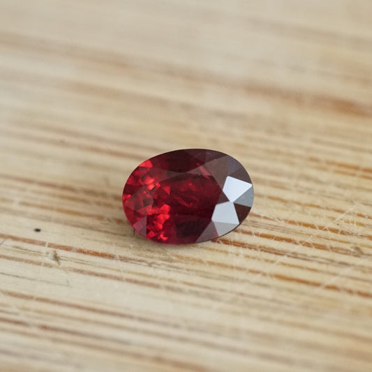 a 0.89 ct oval ruby rests on a light wood base