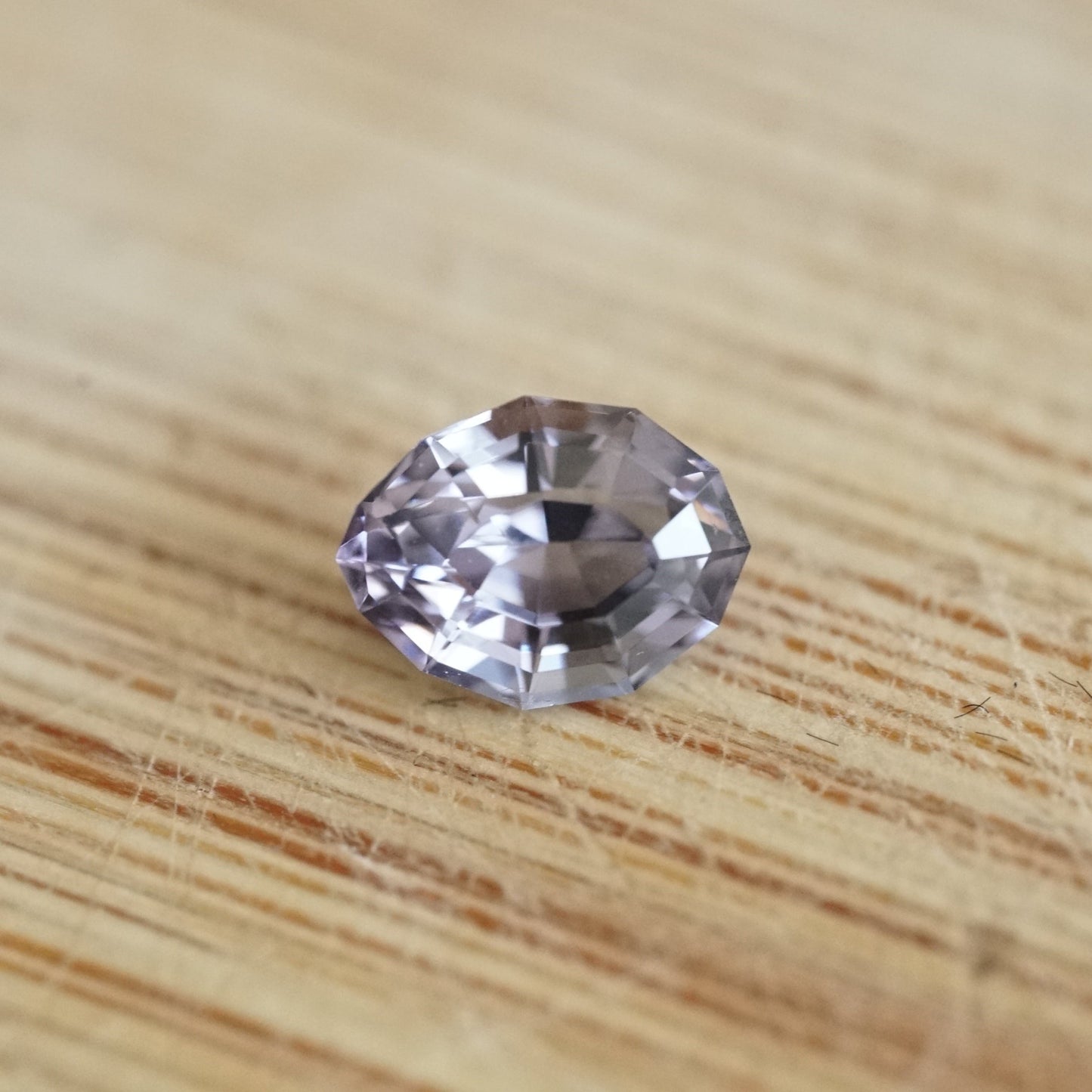 a 1.04 ct lavender spinel in a semi oval-semi pear shape rests on a wood base