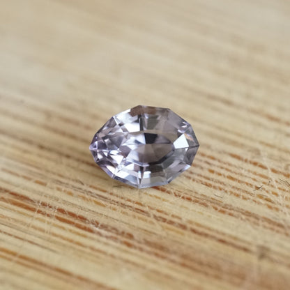 a 1.04 ct lavender spinel in a semi oval-semi pear shape rests on a wood base