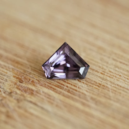 a 1.07 ct dark violet spinel rests on a wood base