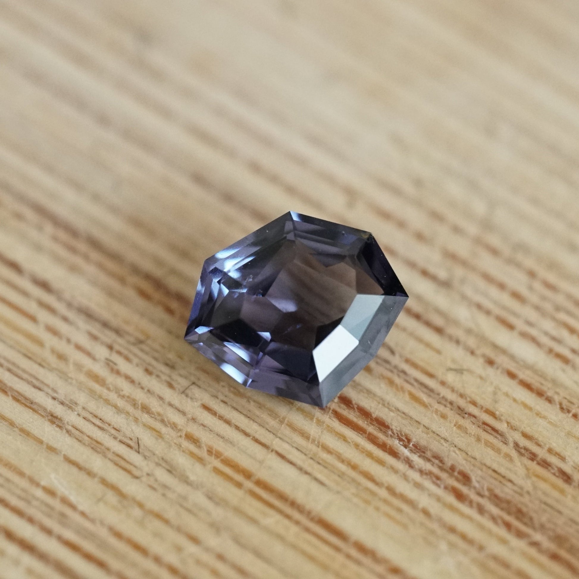 a 1.14 ct dark violet shield shape spinel rests on a wood base