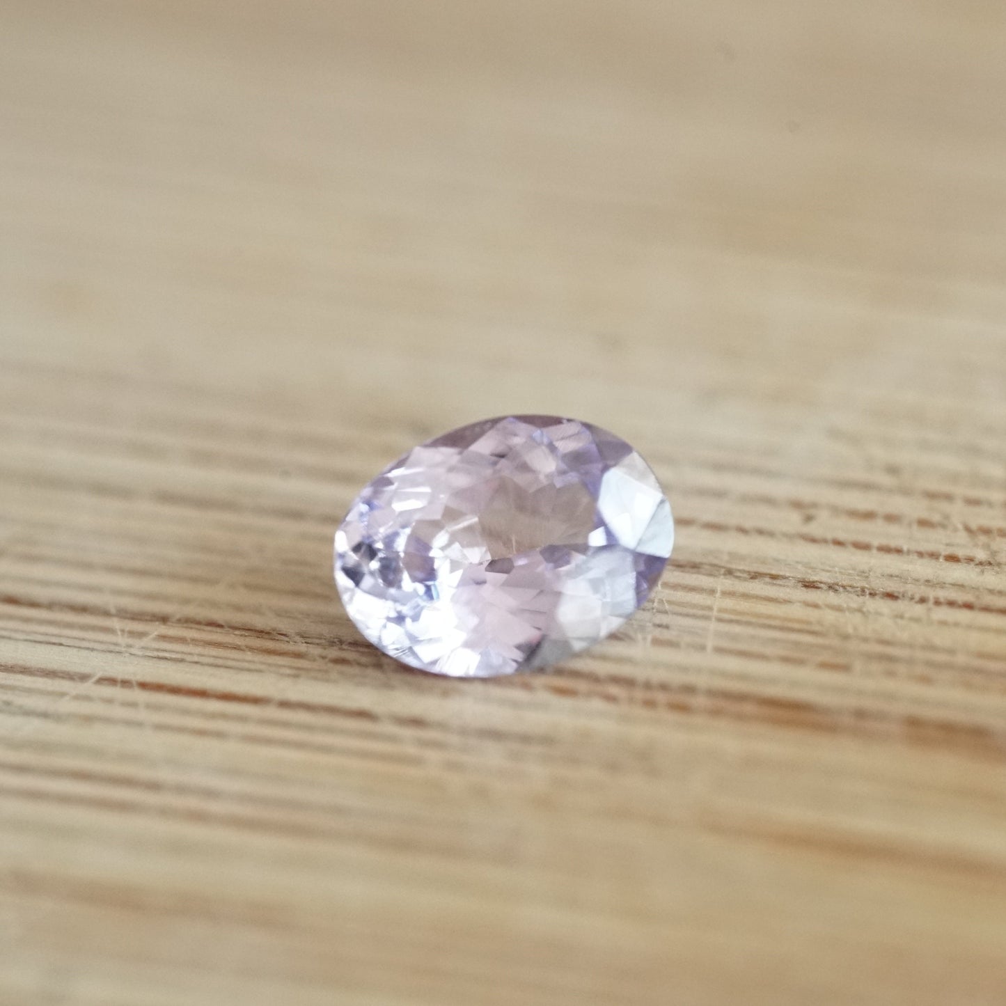 a 1.19 ct oval lavender sapphire rests on a wood base