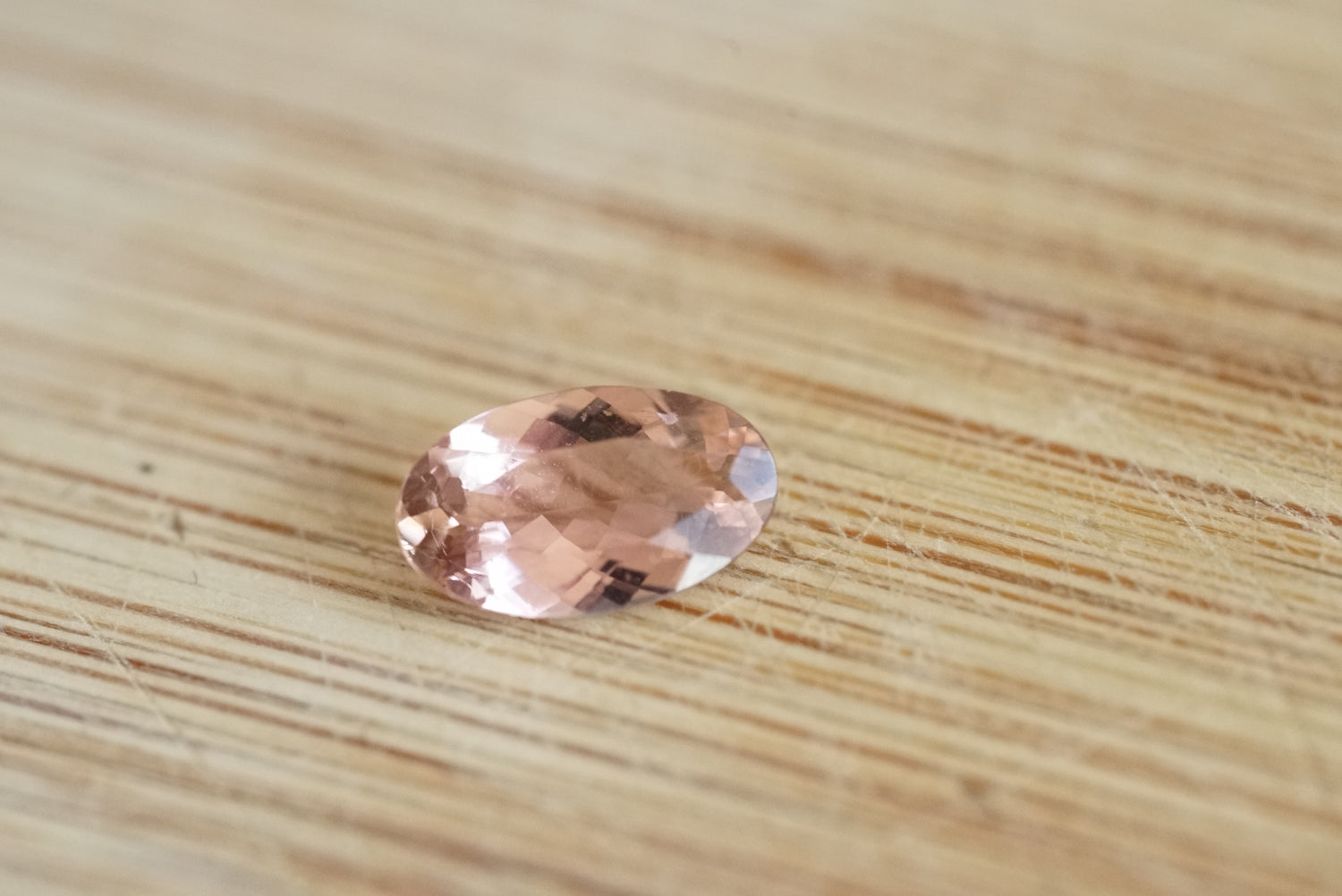 Oval-shaped pink gemstone on a wooden surface