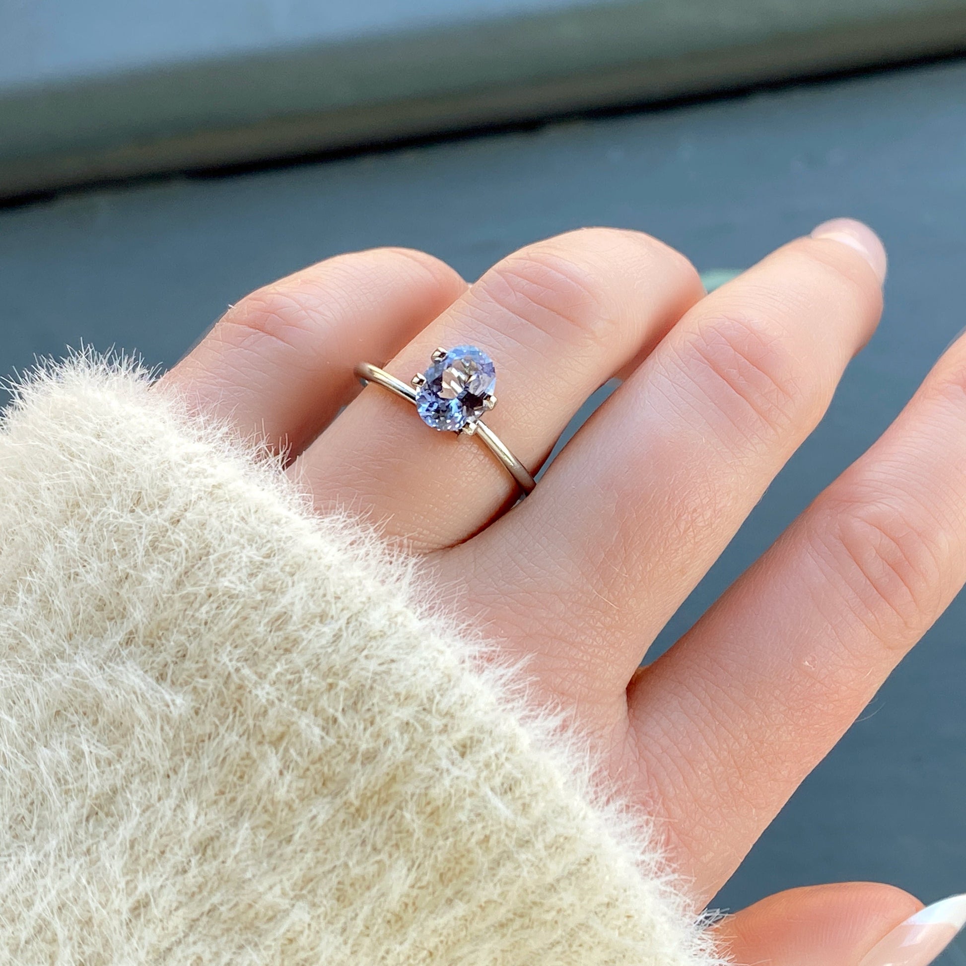 a 1.34 ct oval icey blue sapphire in a temporary ring mounting in diffused winter sunlight