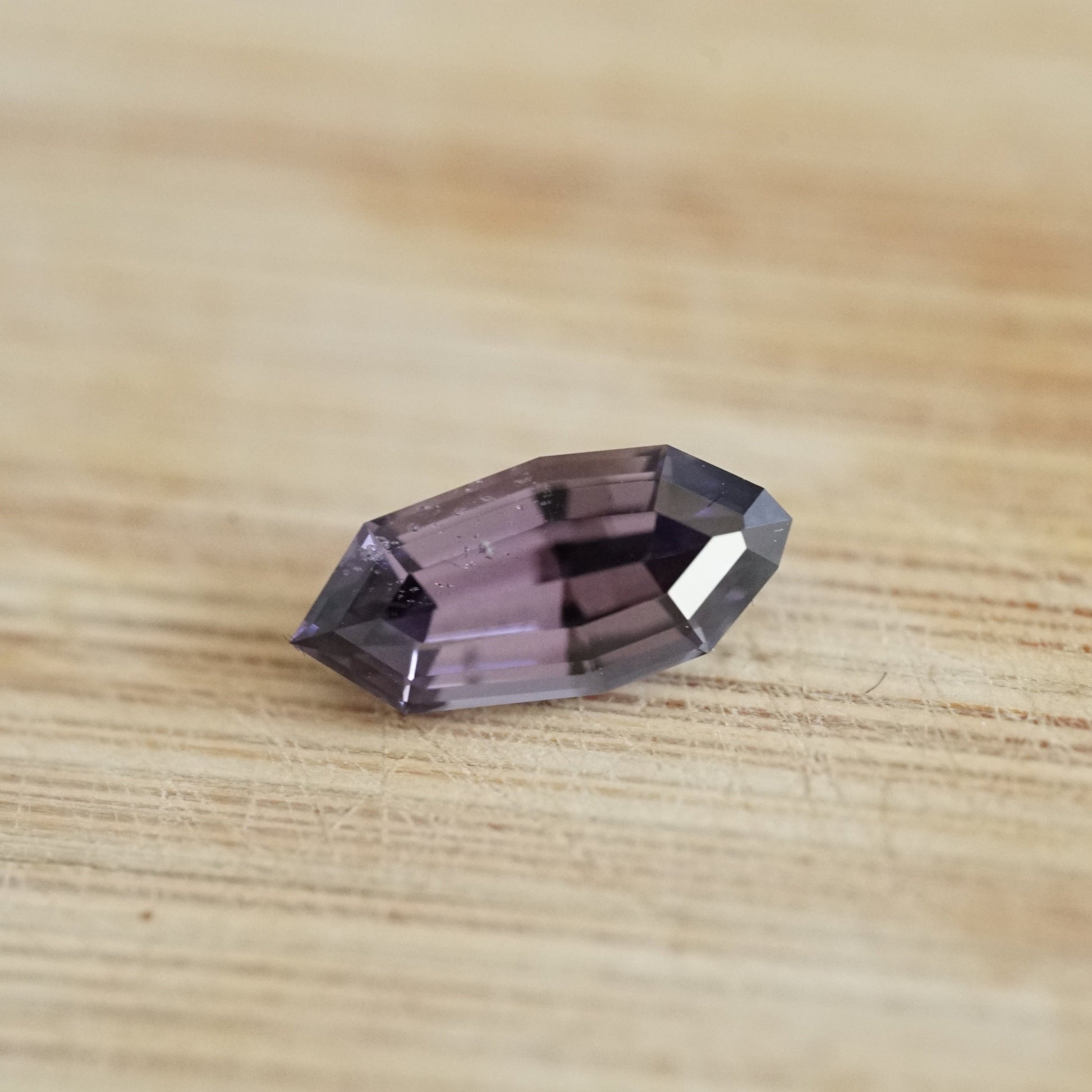 a 1.57 ct violet spinel in a temporary ring mounting on a wood display