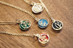 A set of 10K Yellow Gold and Cold Enamel Pendants rests on a wood base