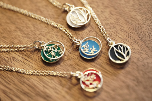 A set of 10K Yellow Gold and Cold Enamel Pendants rests on a wood base