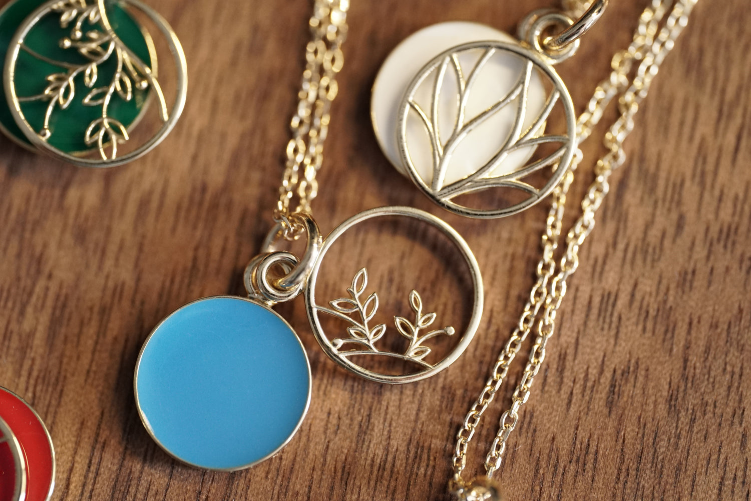 A set of 10K Yellow Gold and Cold Enamel Pendants rests on a wood base