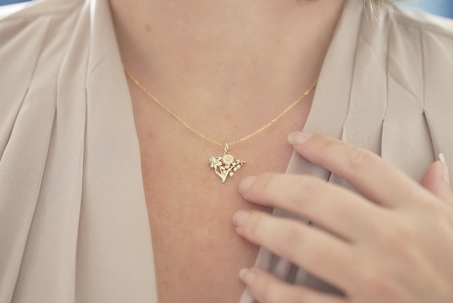 Gold necklace with a pendant worn by a person, with a blurred background