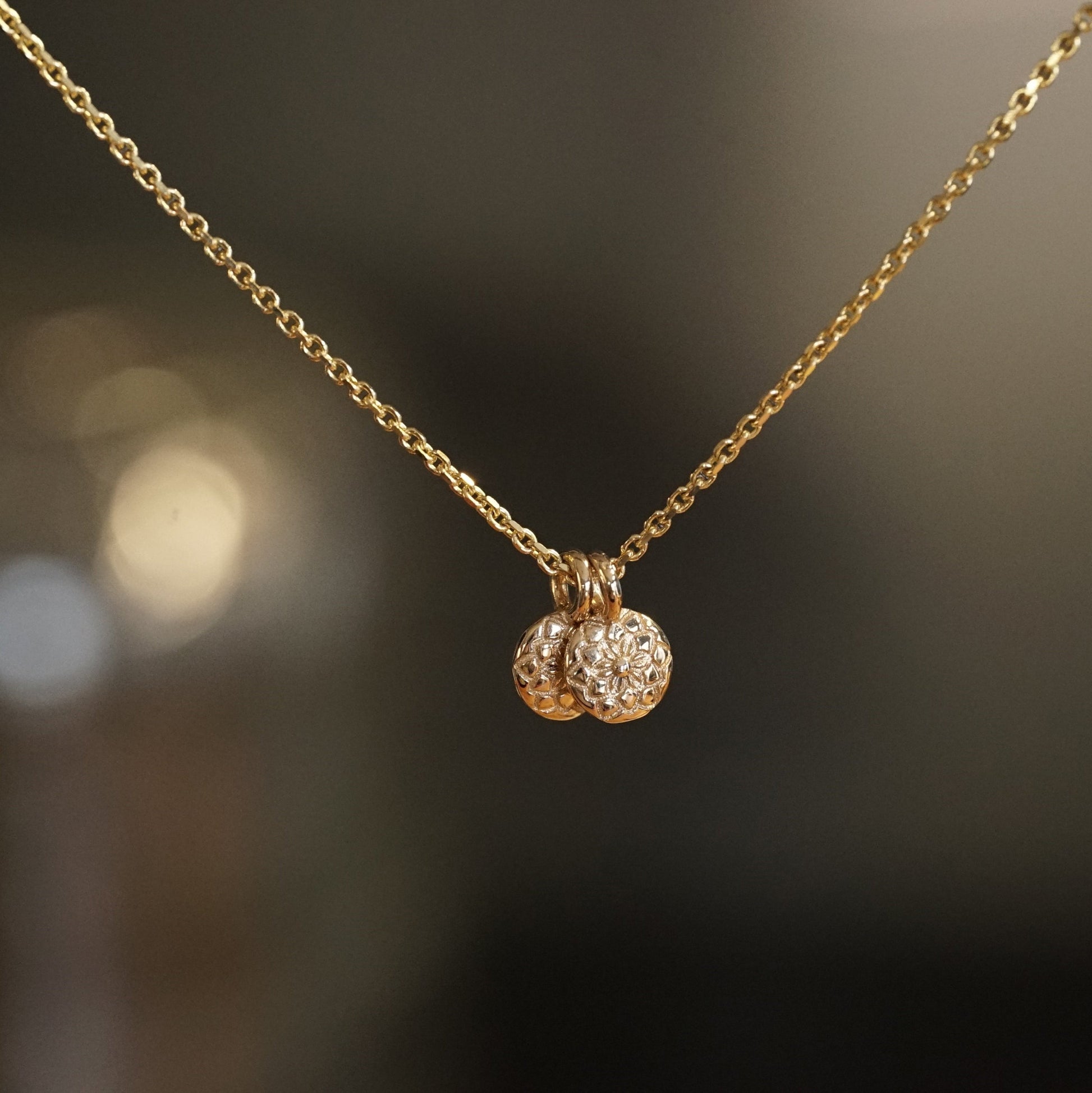 a pair of 14K yellow gold pendants with a custom carved dahlia pattern on a diamond cut cable chain