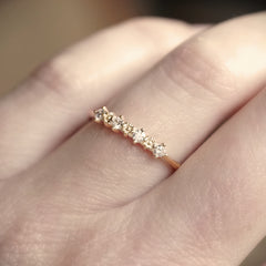 Yellow gold ring with small diamonds on a finger against a blurred background
