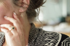 Close-up of a person wearing earrings and a ring, with a blurred background