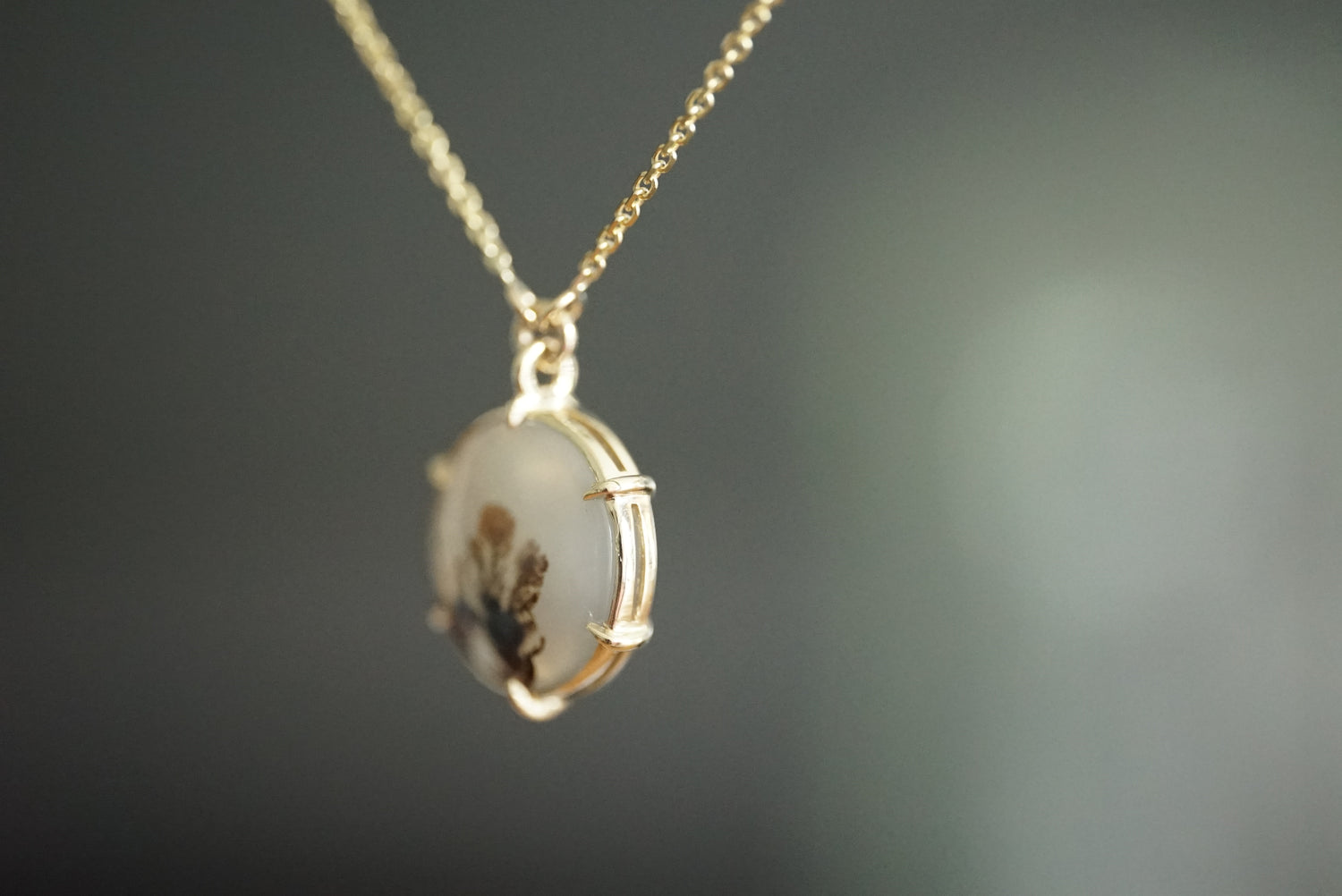 Gold necklace with a pendant on a dark background
