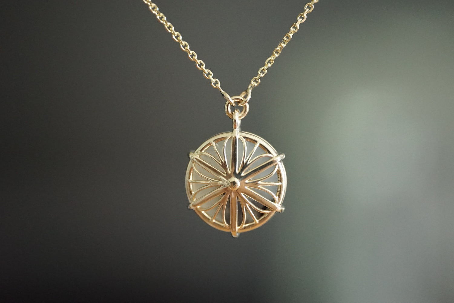 Gold necklace with a circular pendant on a dark background