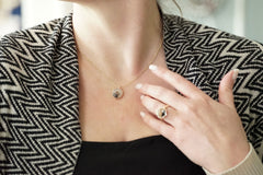 Person wearing a necklace and ring with a blurred background