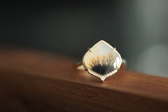 Gold ring with a unique design on a wooden surface
