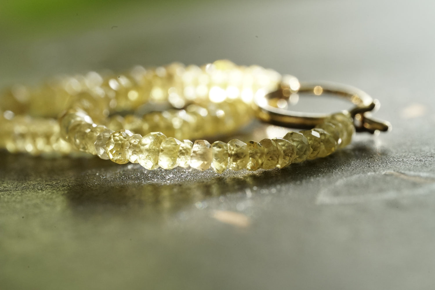 Close-up of Yellow Sapphire hoop earrigs on a reflective surface