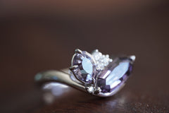 white gold ring with purple gemstone on a wooden surface