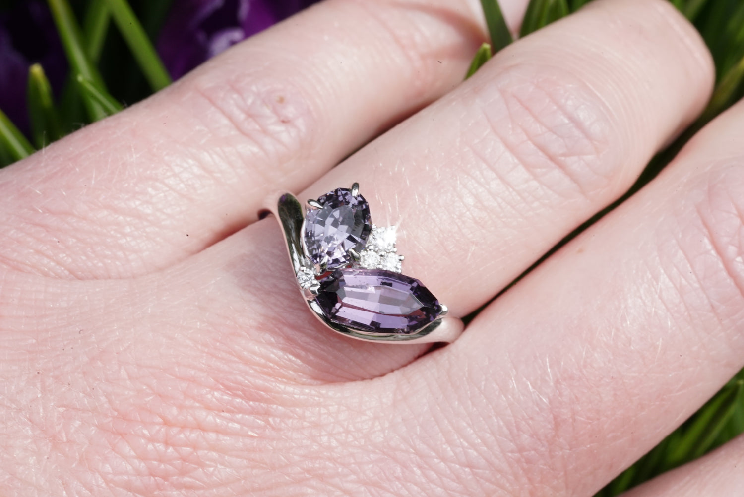 Ring with purple gemstones on a hand against a blurred natural background