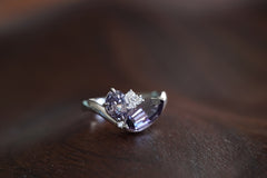 white gold ring with a purple gemstone on a wooden surface