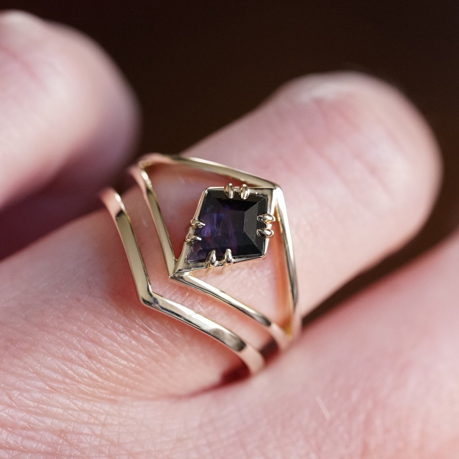Gold ring with a purple gemstone on a finger