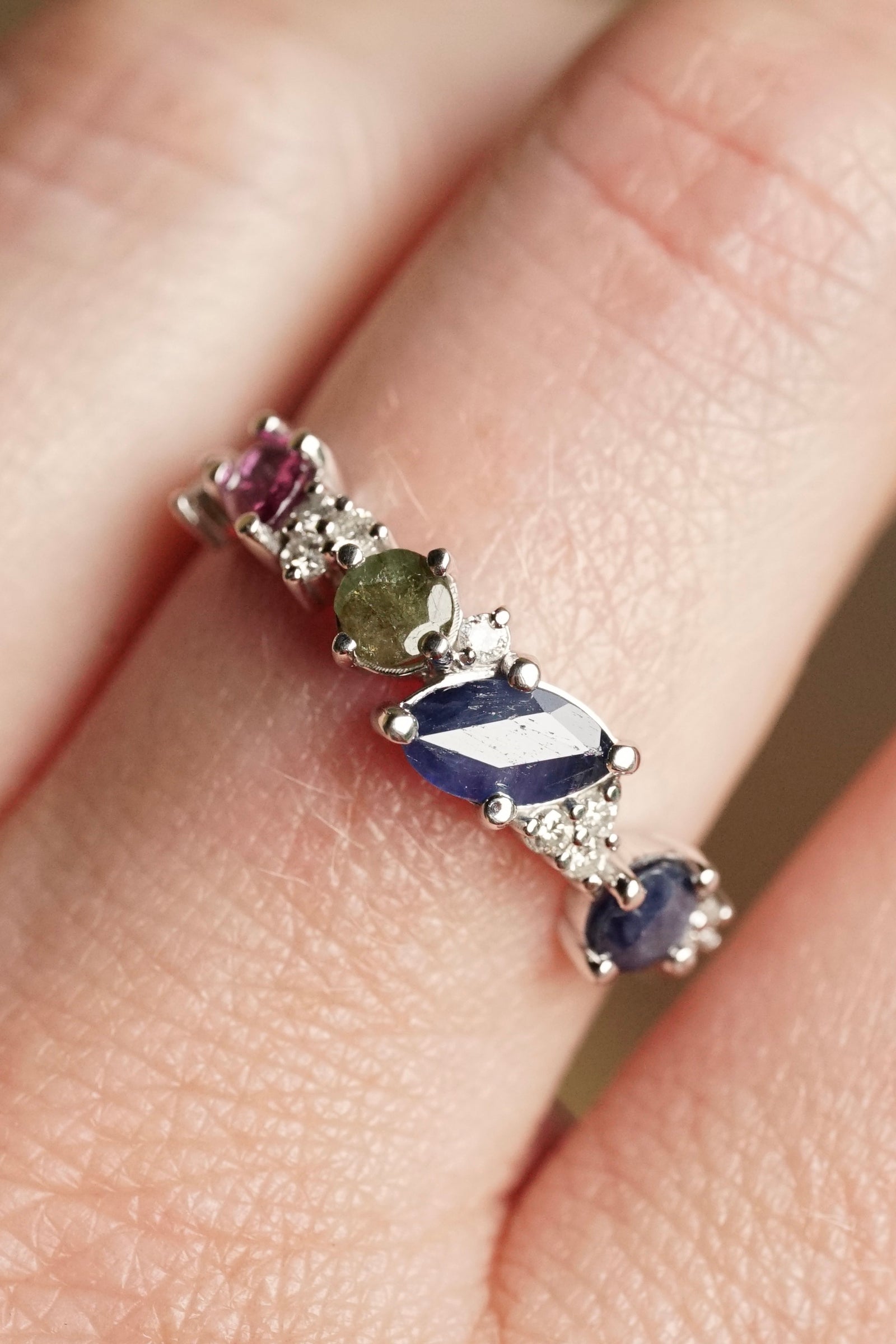 a white gold ring with cambodian sapphires emeralds and rubies on a light skin tone hand